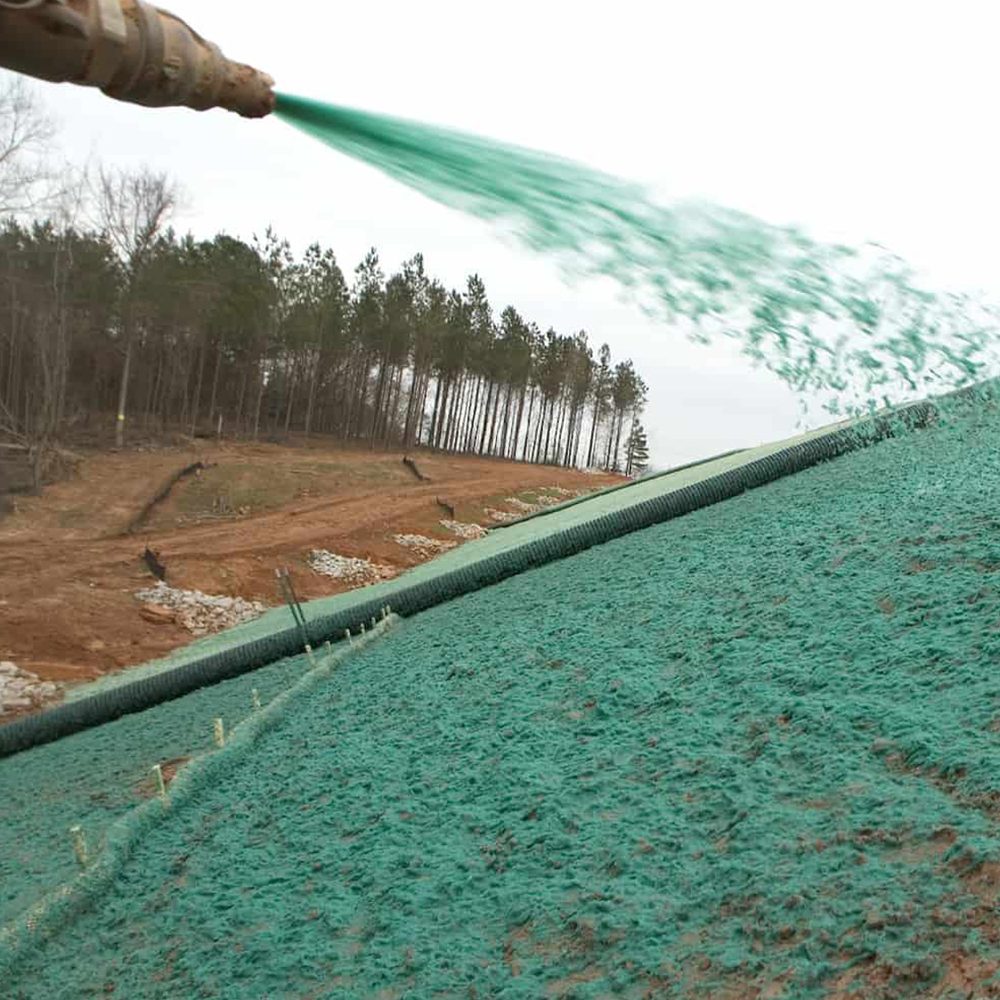 Spraying green hydroseed slurry onto a graded slope